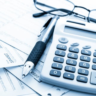 Pen next to glasses and a ten-key calculator